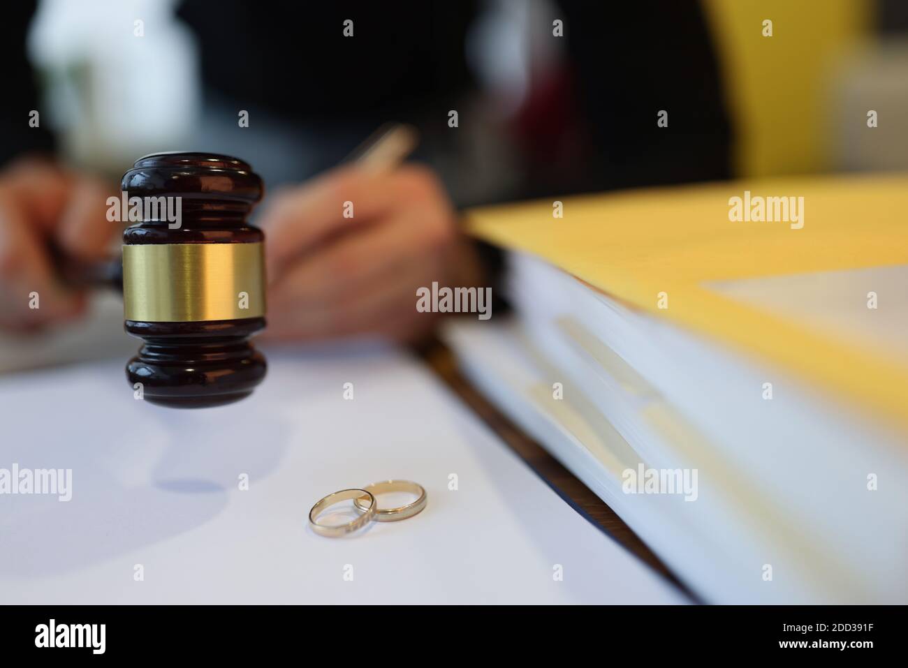 Richter hält hölzernen Gavel in der Nähe von zwei Eheringe close-up Stockfoto