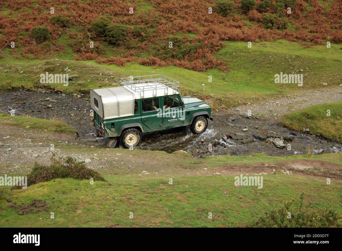 Ein National Trust Ranger's Land Rover, der einen Bach im Carding Mill Valley überquert, Shropshire, England, Großbritannien. Stockfoto