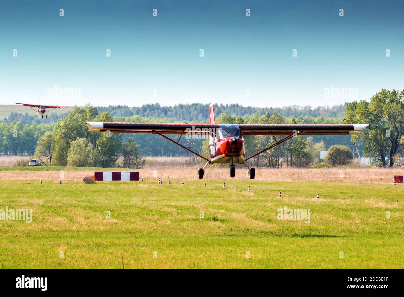 Landung von zwei roten Privatflugzeugen nacheinander bei Ein kleiner Flugplatz Stockfoto