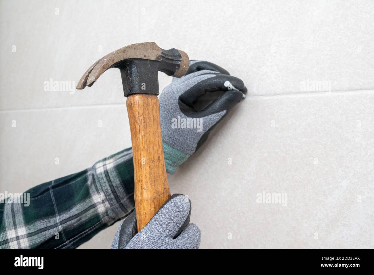 Die Hand des Mannes hält einen Hammer und nagelt die Wand. Stockfoto