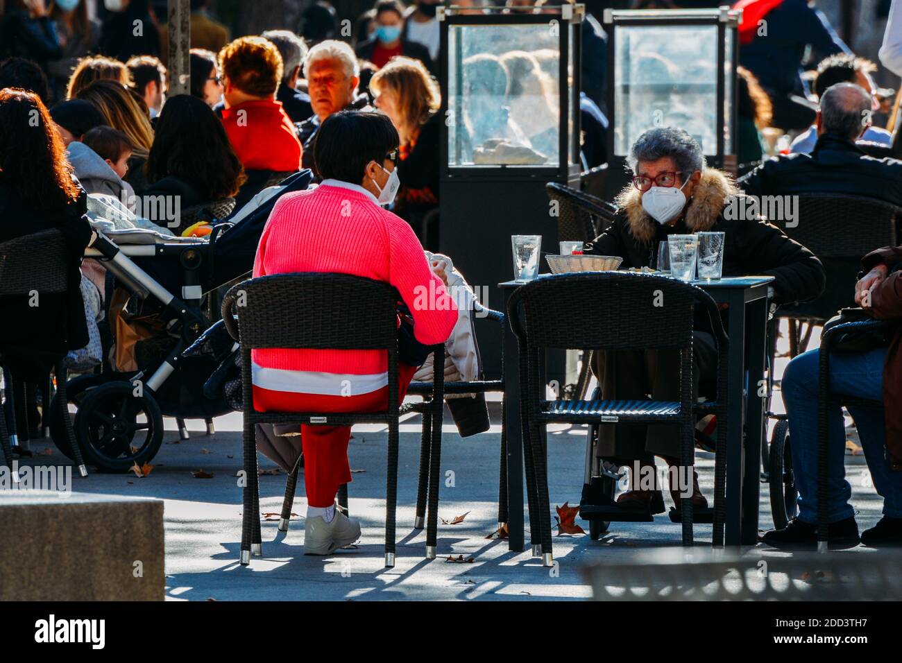 Madrid / Spanien - Nov 21, 2020: Die Menschen entspannen sich auf der Terrasse Café im beliebten Malasana-Viertel im Zentrum von Madrid, Spanien. Einige tragen Gesichtsmasken Stockfoto