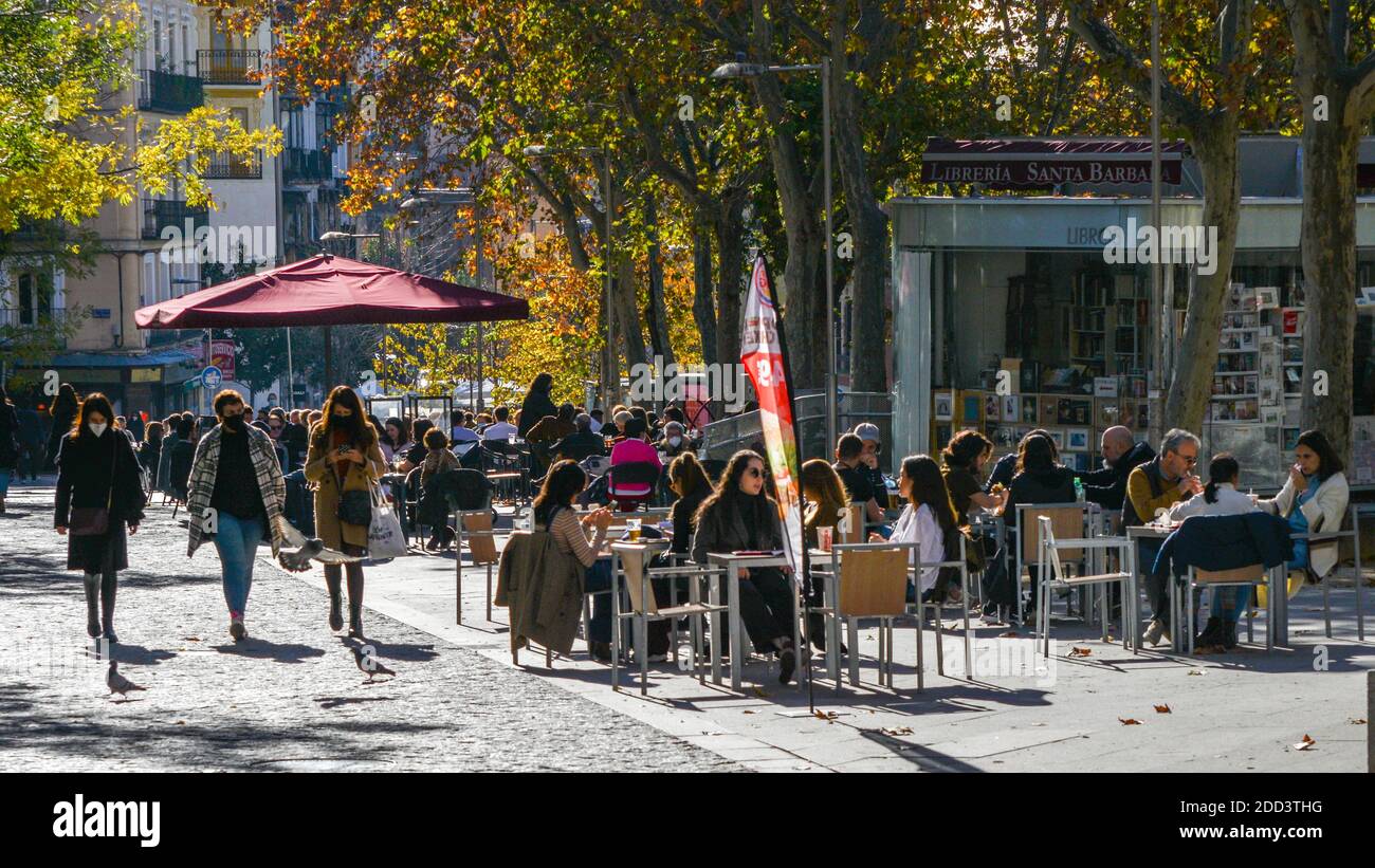 Madrid / Spanien - Nov 21, 2020: Die Menschen entspannen sich auf der Terrasse Café im beliebten Malasana-Viertel im Zentrum von Madrid, Spanien. Einige tragen Gesichtsmasken Stockfoto