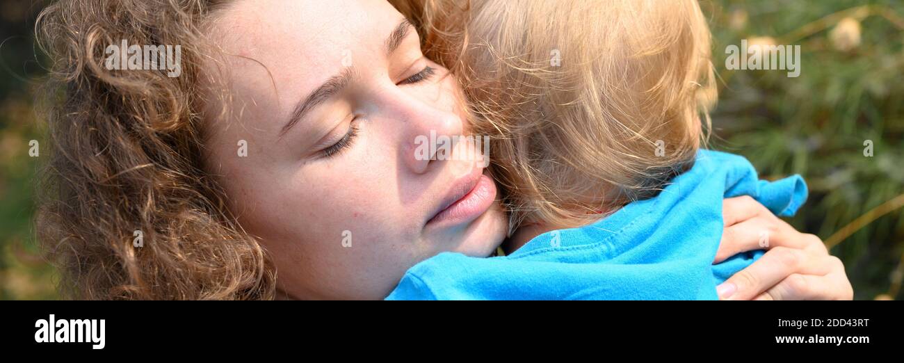 Mama hält ihren kleinen Jungen in den Armen, um sich zu entschuldigen, umarmt das Kind seine Mutter und schmiegt sich an sie. Banner Stockfoto