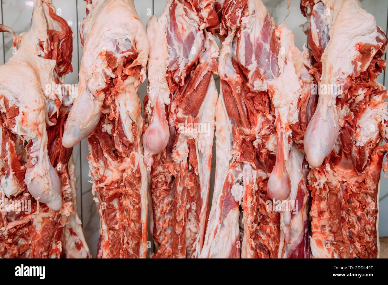 Aufhängen von Schafsfleisch in der Metzgerei. In einem Schlachthaus schneiden und hängen die Rasseln an Haken. Halal-Schneiden. Stockfoto