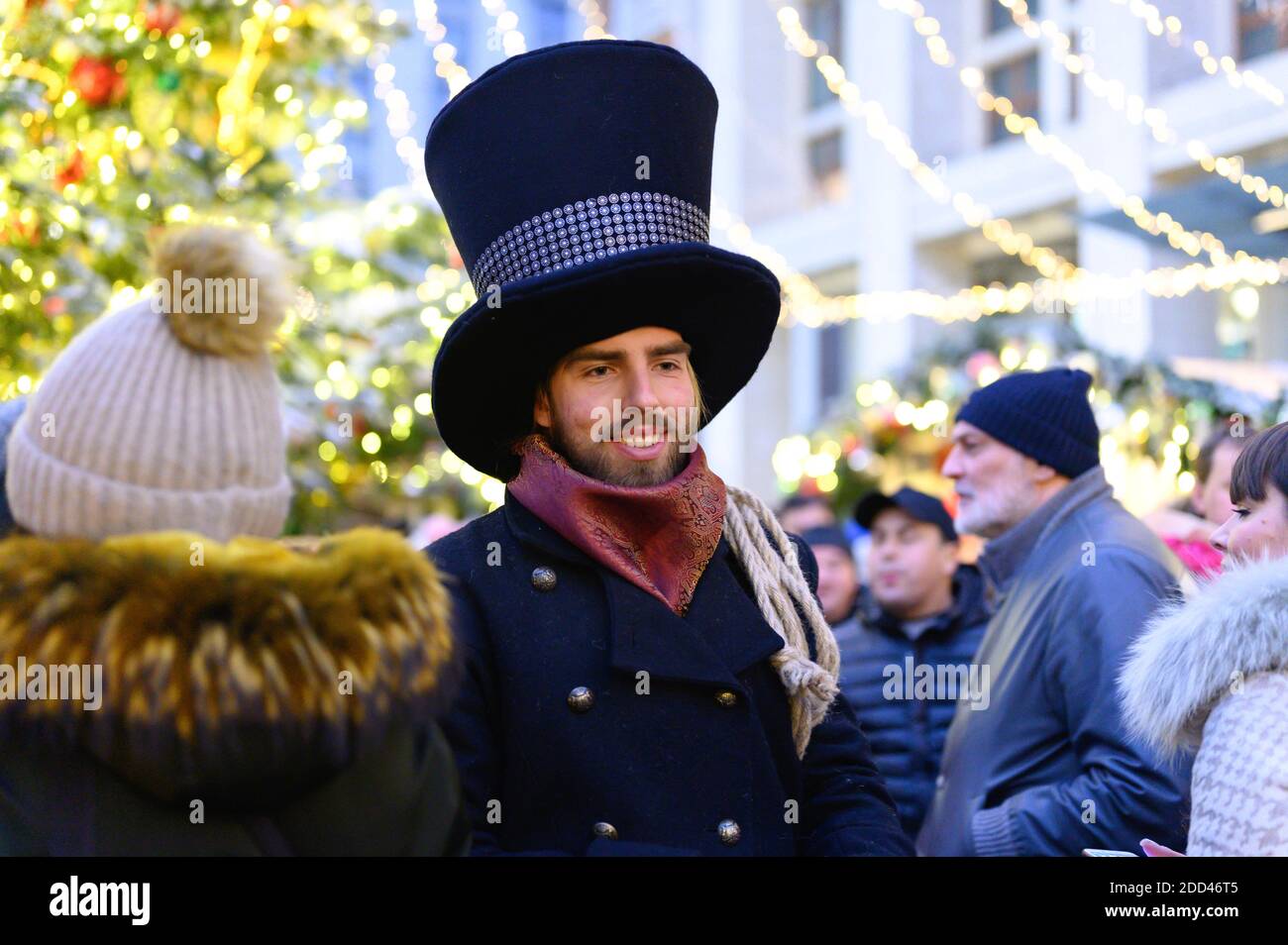 Moskau / Russland - Dezember 2019: Ein Mann in einem schicken Kleid mit einem Hut geht die Straße in einer Menge von Menschen in der Silvesternacht Stockfoto