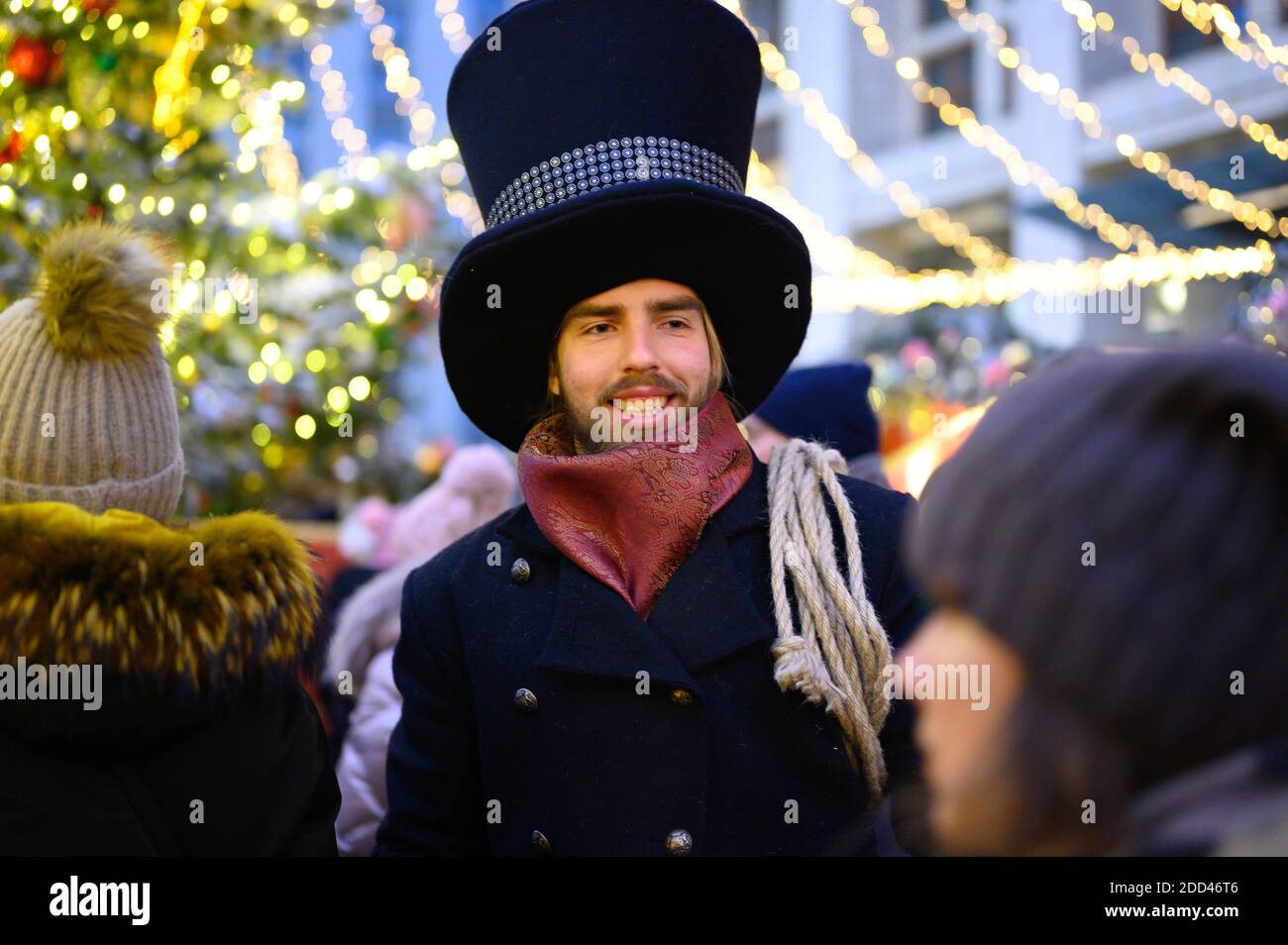 Moskau / Russland - Dezember 2019: Ein Mann in einem schicken Kleid mit einem Hut geht die Straße in einer Menge von Menschen in der Silvesternacht Stockfoto