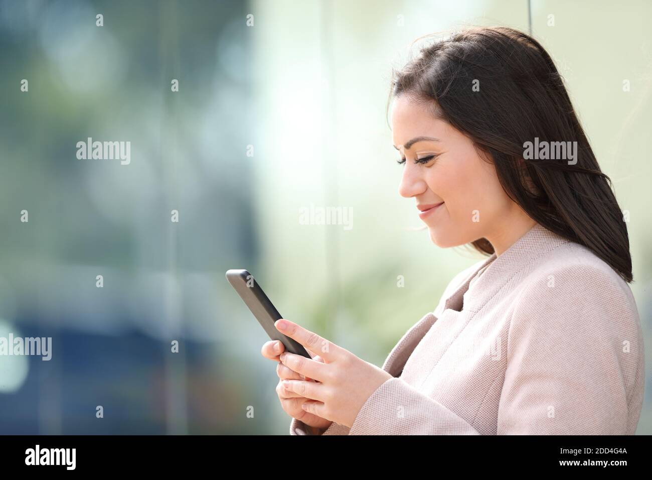 Seitenansicht einer Geschäftsfrau, die Text auf einem Smartphone liest Auf der Straße Stockfoto