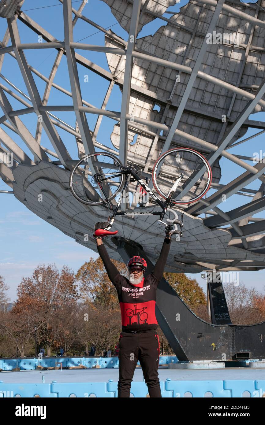 Ein Foto von einem Mitglied des Brothers United Bicycle Club mit der Unisphere im Hintergrund. Stockfoto