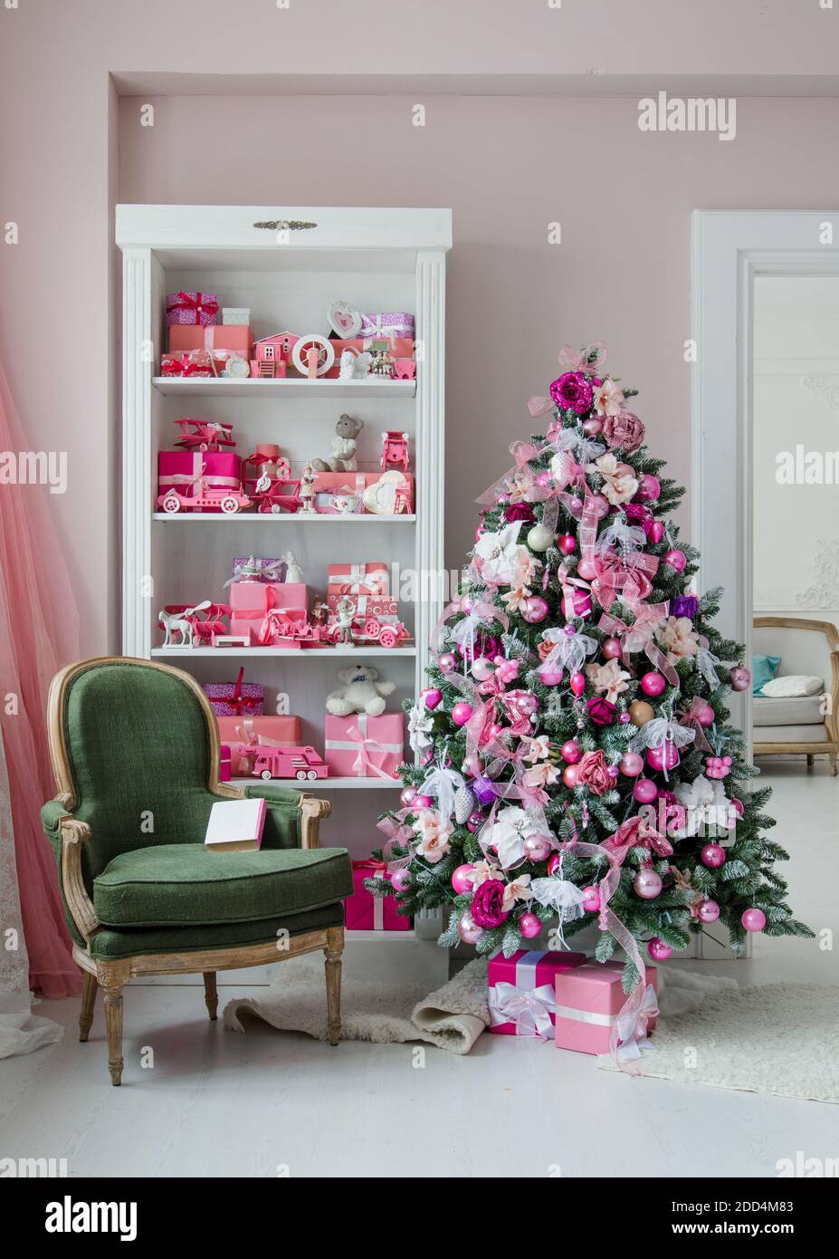 Innenraum in Weihnachtsstil eingerichtet. Keine Menschen. Einen leeren grünen Stuhl. Rosa Farben. Komfort des modernen Hauses. Stockfoto