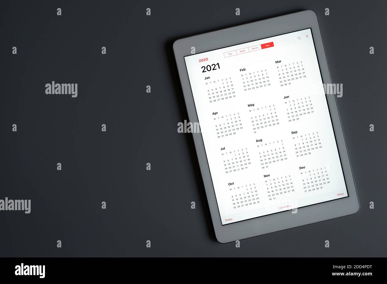 Eine Tablette mit einem offenen Kalender für 2021 Jahre auf einem dunkelgrauen hintergrundeine Tablette mit einem offenen Kalender für 2021 Jahre auf einem dunkelgrauen Hintergrund. Raum fo Stockfoto