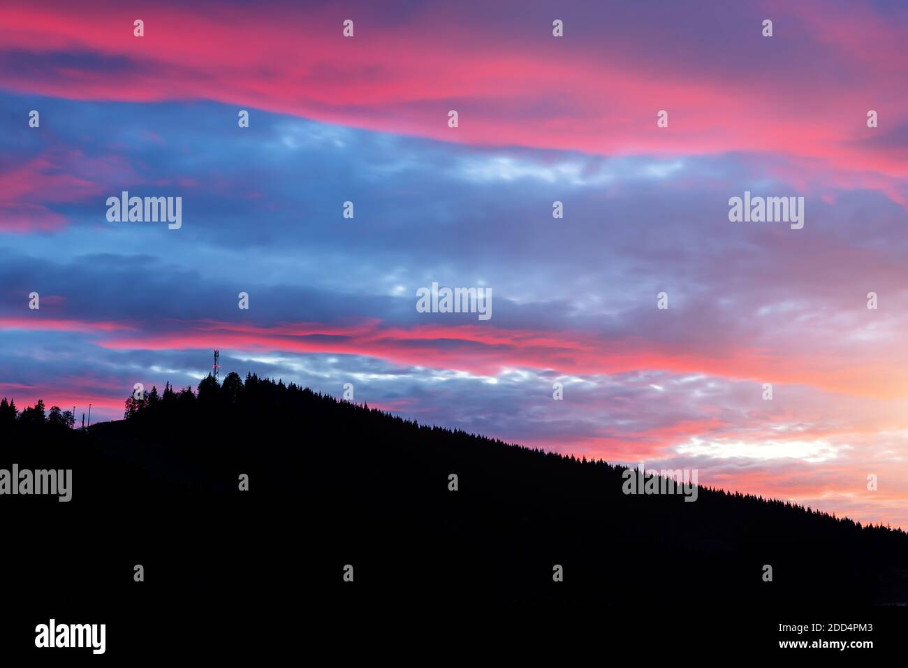 Szenische dramatische feurig bewölkt Sonnenuntergang Abend Blick über Bergresort Dorf Bukovel in der Ukraine mit Kiefernwald weihnachtsbaum Silhouetten Stockfoto
