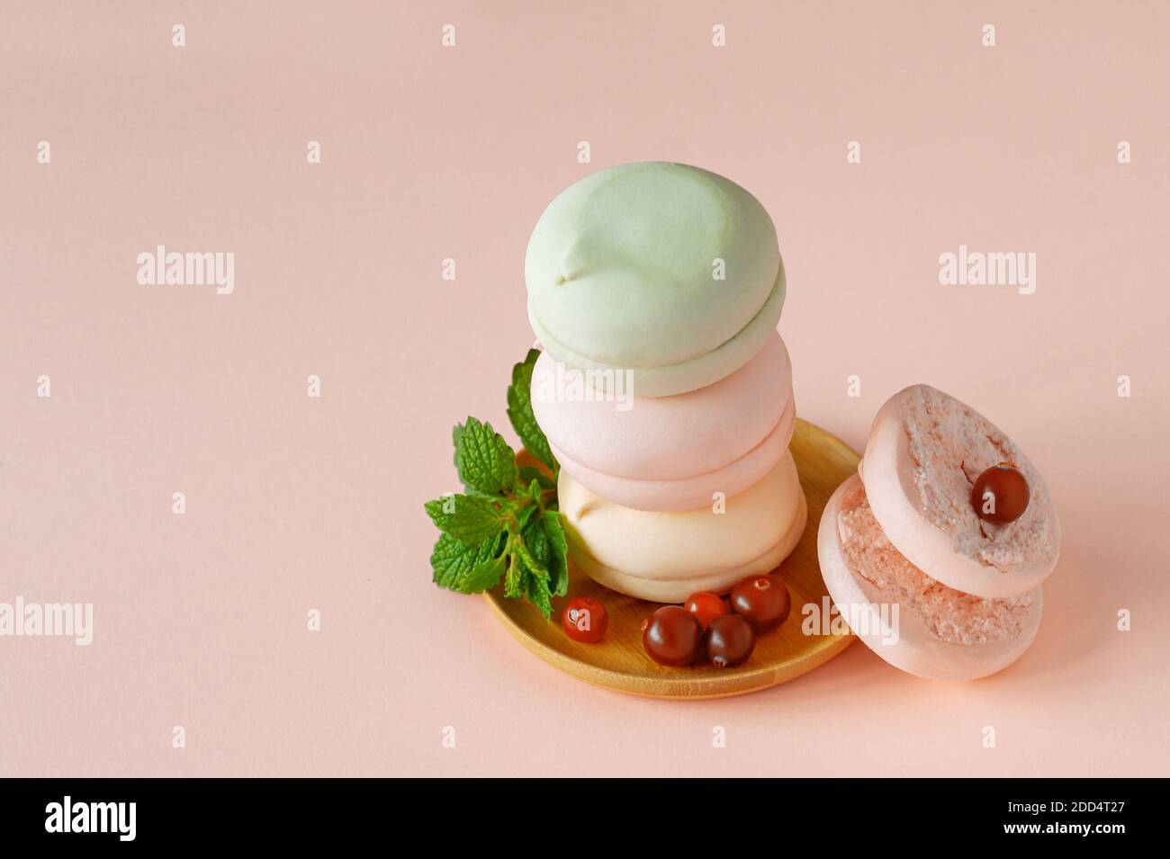 weihnachtskomposition mit hausgemachtem Pastell mehrfarbigem zephyr in runder Form, grüner Kerze und Tannenzweigen. Stockfoto