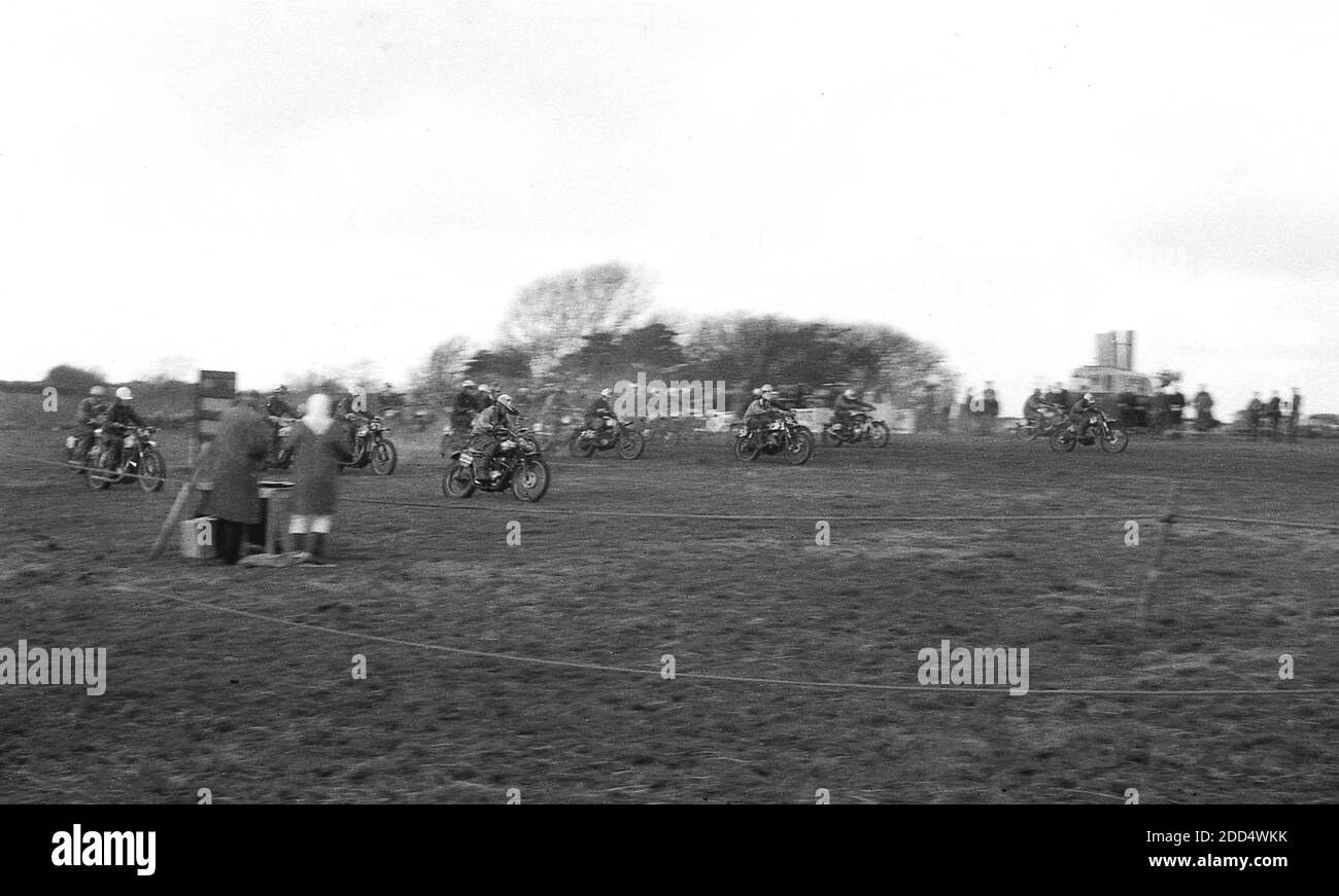 1950er Jahre, historisch, Beginn einer Motorradjagd Wettbewerber auf Motorrädern, die an einem Rennen oder einem Motorcross teilnehmen. Camberley in Surrey war 1924 Austragungsort des ersten Scramble-Rennens. In den folgenden Jahren wuchs der Sport an Popularität, insbesondere in Großbritannien, wo Teams der klassischen britischen Motorradhersteller, darunter die Birmingham Small Arms Company (BSA), Norton, Matchless, Rudge und AJS, an Rennen teilnahmen. Stockfoto