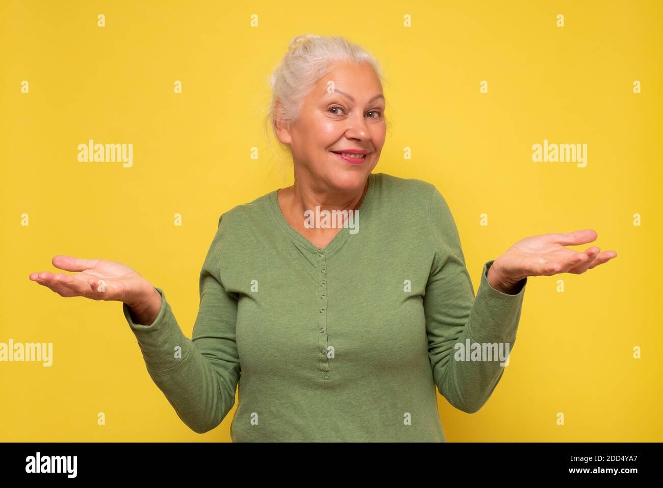 Lächle ältere Frau, die etwas auf offenen Handflächen hält. Studioaufnahme. Stockfoto