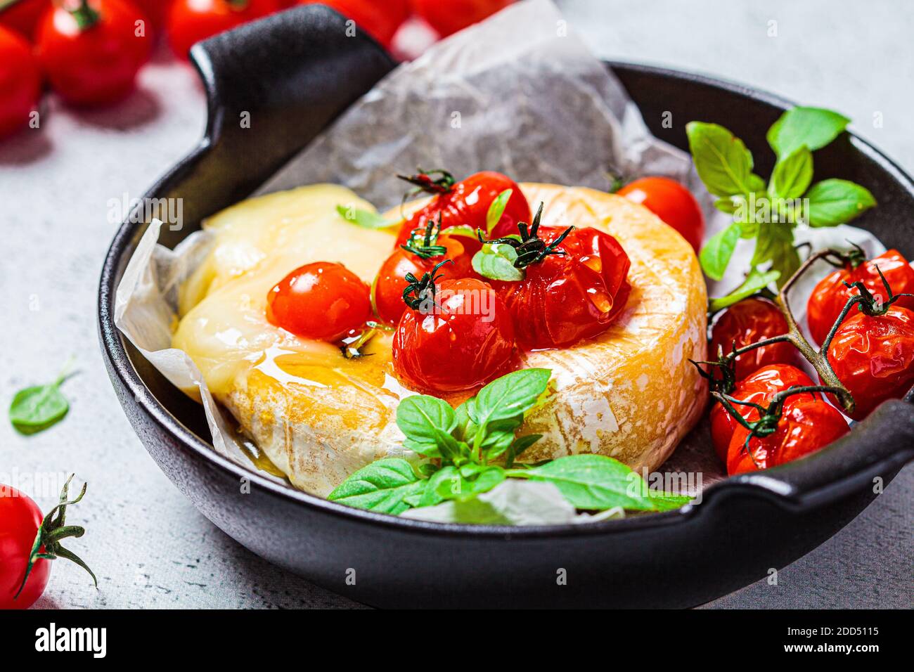 Gebackenen Camembert oder Brie Käse mit Tomaten in einer schwarzen Pfanne. Stockfoto