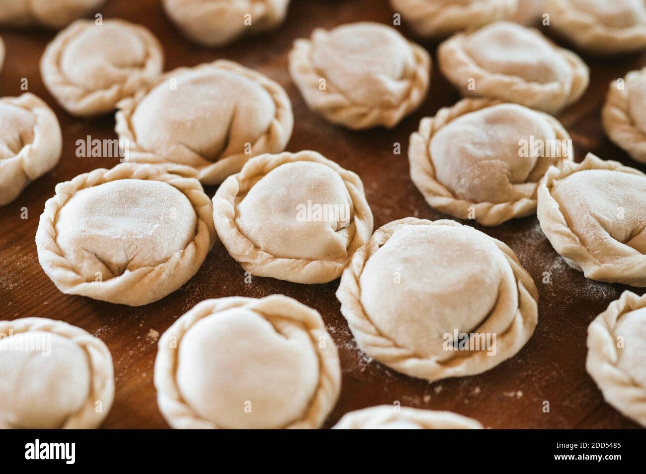 Haufen von kleinen hausgemachten ungekochten Knödel mit Fleisch auf Küchentisch. Nationale traditionelle russische Küche. Tun Sie es selbst. Draufsicht, Flet legen Stockfoto