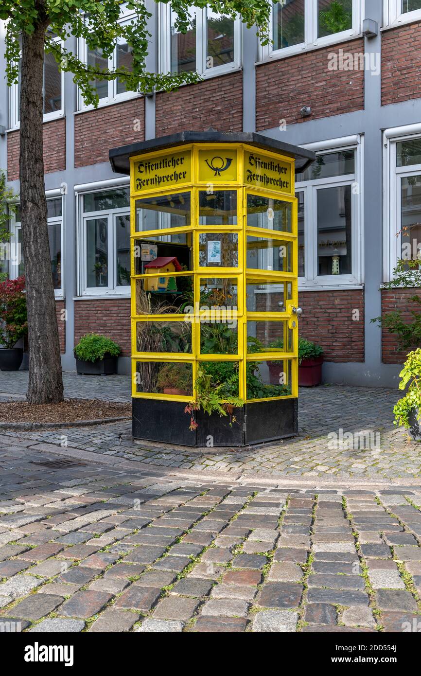 Schöne alte öffentliche Telefonbox, die in einen kleinen Gewächshausgarten umgewandelt wurde. Umgeben von schönen Hütten in Schnoor, Bremen, Deutschland Stockfoto