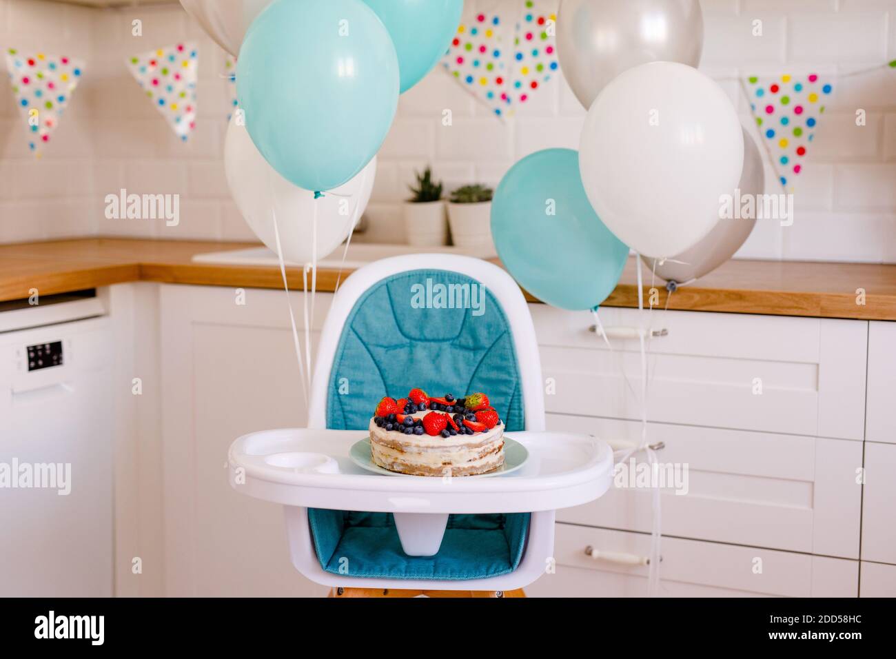 Kinderhochstuhl ist mit blauen und weißen Kugeln geschmückt, um den ersten Geburtstag zu feiern. Stockfoto
