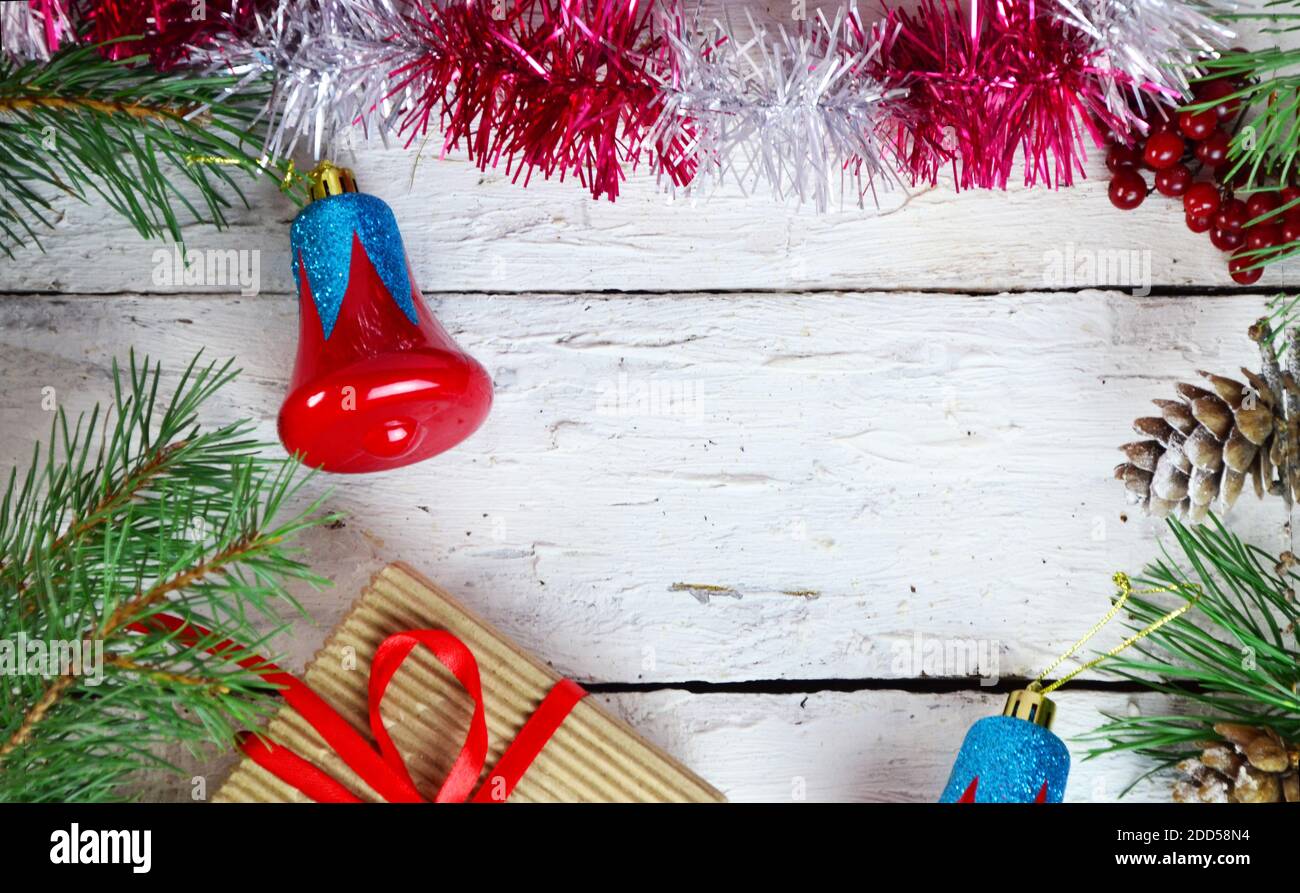 Weihnachten oder Neujahr Komposition. Weihnachtsgeschenk, zwei Weihnachtsdekorationen rot blaue Glocke, Tannenzapfen, Tannenzweige auf Holz weißen Hintergrund. Flach l Stockfoto