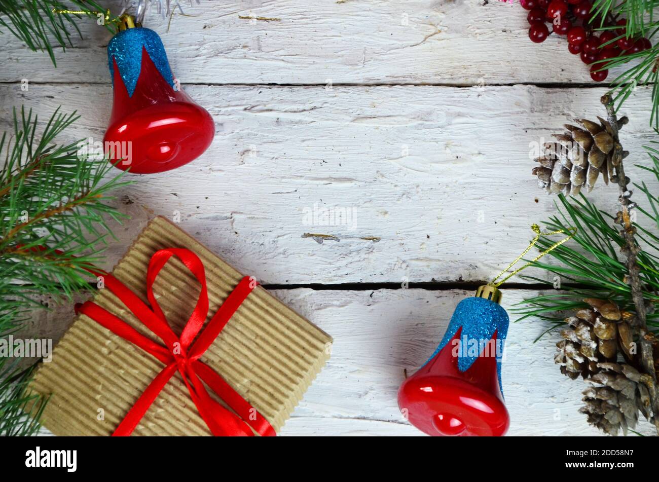 Weihnachten oder Neujahr Komposition. Weihnachtsgeschenk, zwei Weihnachtsdekorationen rot blaue Glocke, Tannenzapfen, Tannenzweige auf Holz weißen Hintergrund. Flach l Stockfoto