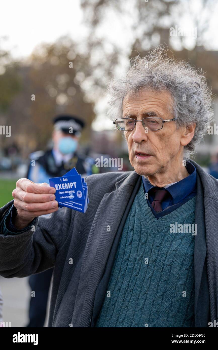 London, Großbritannien. November 2020. Piers Corbyn (Bruder des ehemaligen Labour-Führers Jeremy Corbyn) führte einen kleinen Anti-vax-Anti-Maskenprotest an und verteilte Maskenausnahmemarken an Passanten und die Medien. Er wurde von einem Mann begleitet, der eine riesige Spritze trug, der von der Polizei auf der Westminster Bridge befragt wurde. Kredit: Ian Davidson/Alamy Live Nachrichten Stockfoto