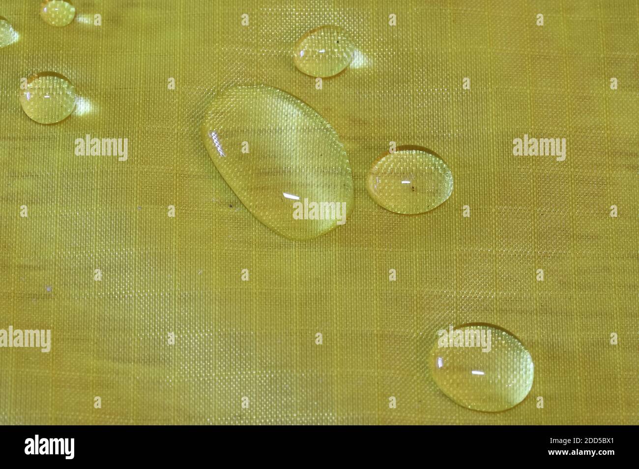 Wassertropfen auf gelbem Stoff Stockfoto