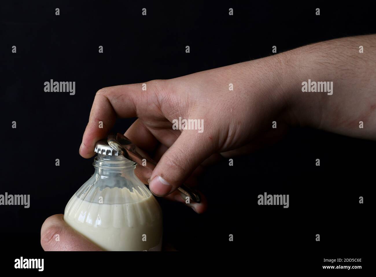 Eine Flasche Milch mit einem Öffner von Hand öffnen Stockfoto