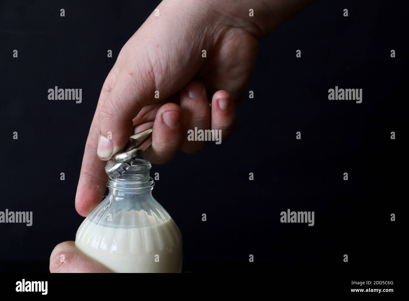 Eine Flasche Milch mit einem Öffner von Hand öffnen Stockfoto