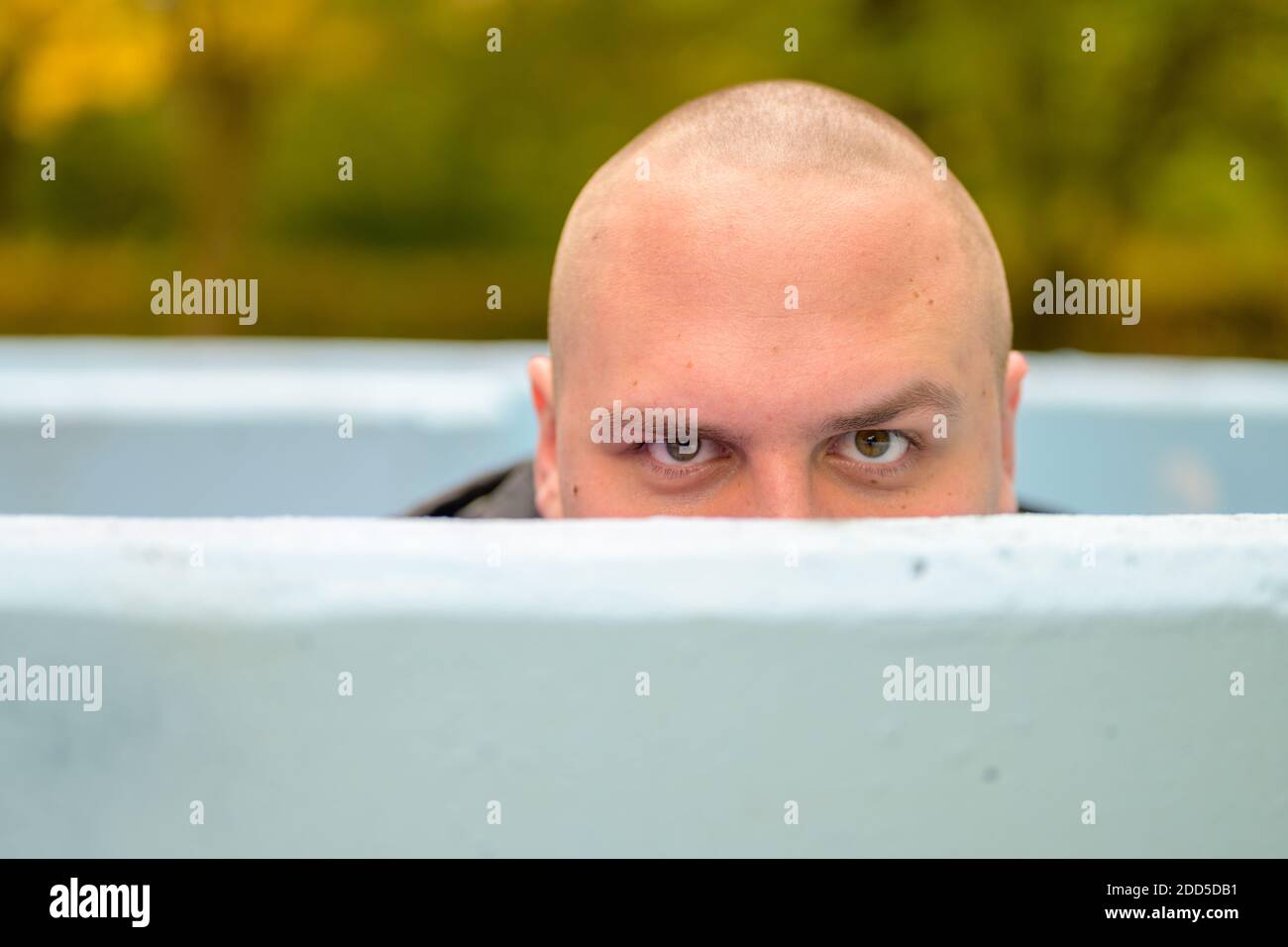 Junger Mann mit rasierten Kopf, der im Freien herunterkommt Badewanne oder Pool, die über den Rand gucken Stockfoto