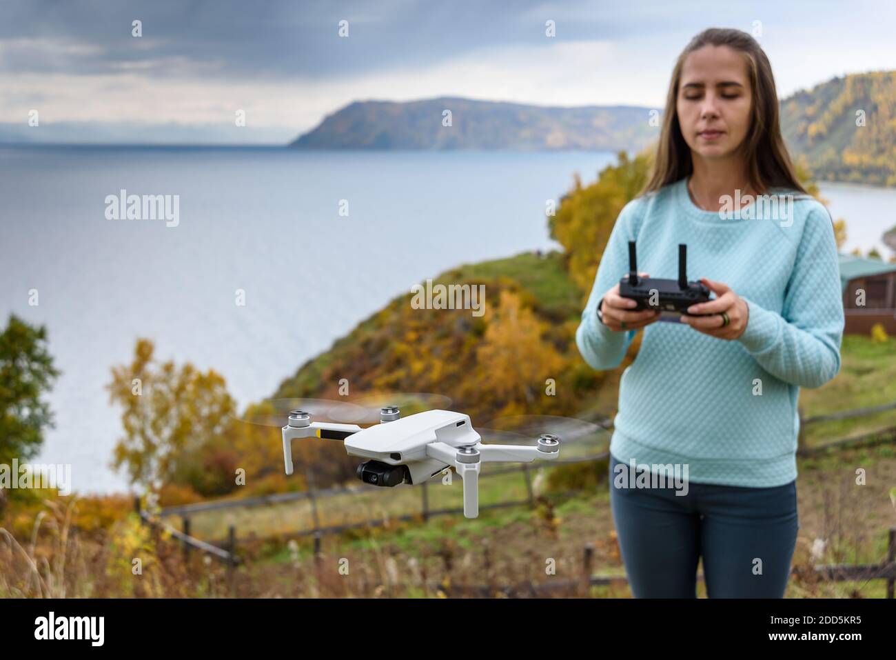 Verschwommene Figur des Mädchens steuert eine Drohne auf Herbst verschwommen Hintergrund. Weichfokus-Konsept Stockfoto