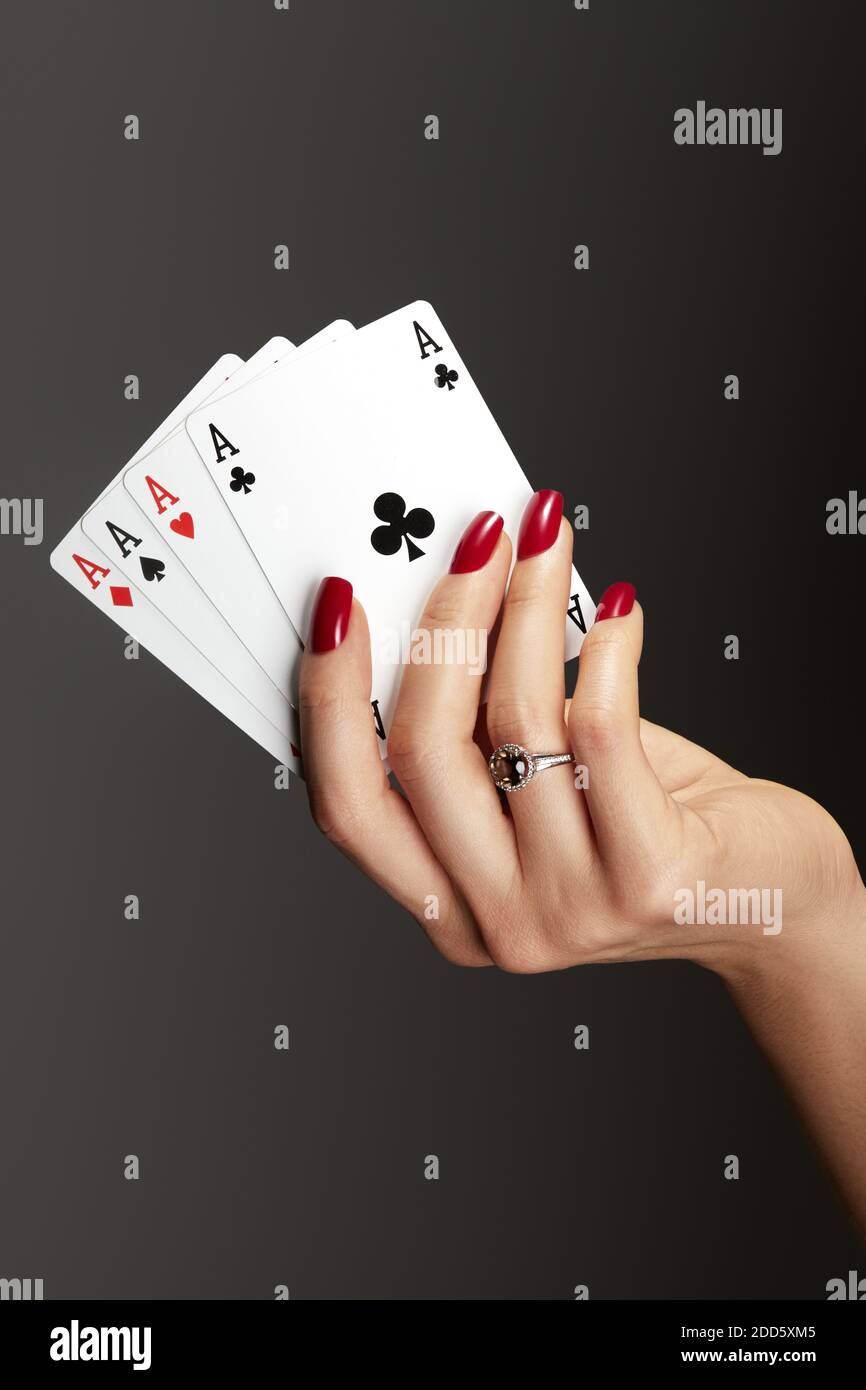 Vier Asse spielen Karten in der Hand der Frau. Spieler mit Poker Quads Kombination. Elegante weibliche Hände mit roter Maniküre auf den Nägeln. Stockfoto