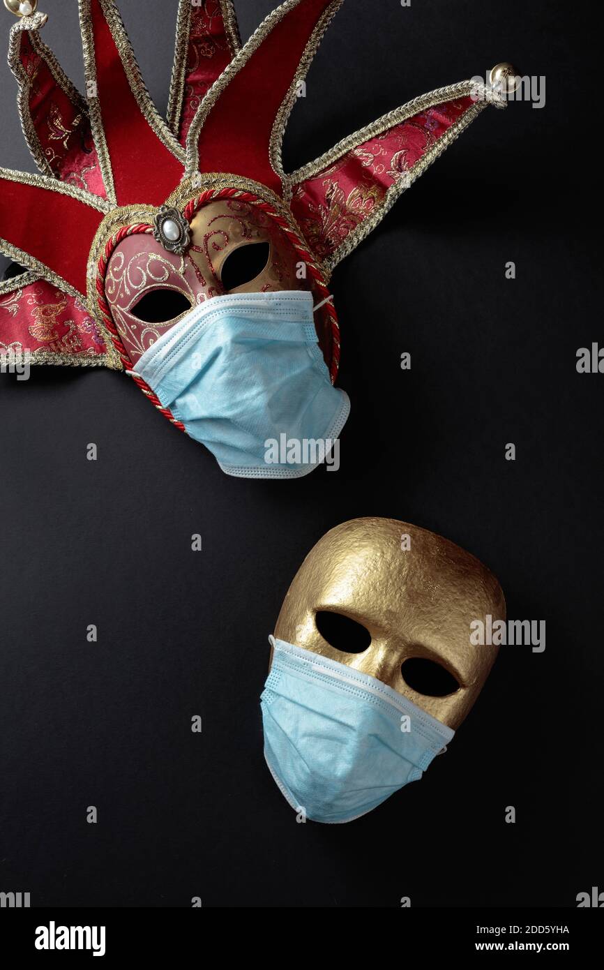 Karnevalsmasken in Schutzmasken. Konzeptuelles Bild des Themas des Virus. Speicherplatz kopieren. Stockfoto