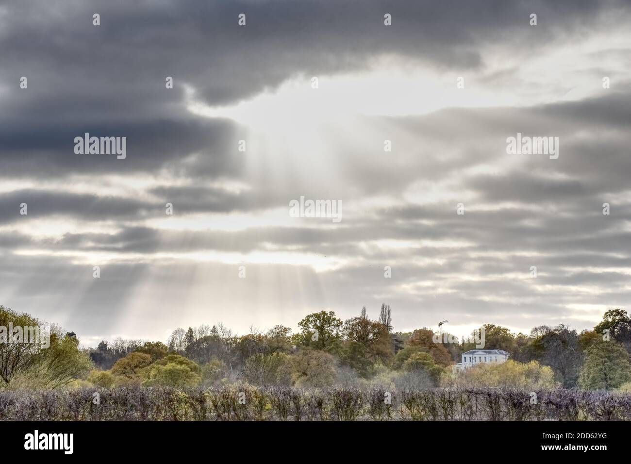 Sonnenstrahlen durch eine dunkle Wolke auf diesem Foto aufgenommen Von der Wiese bei Runnymede in Egham auf einer bedeckten Herbsttag Stockfoto