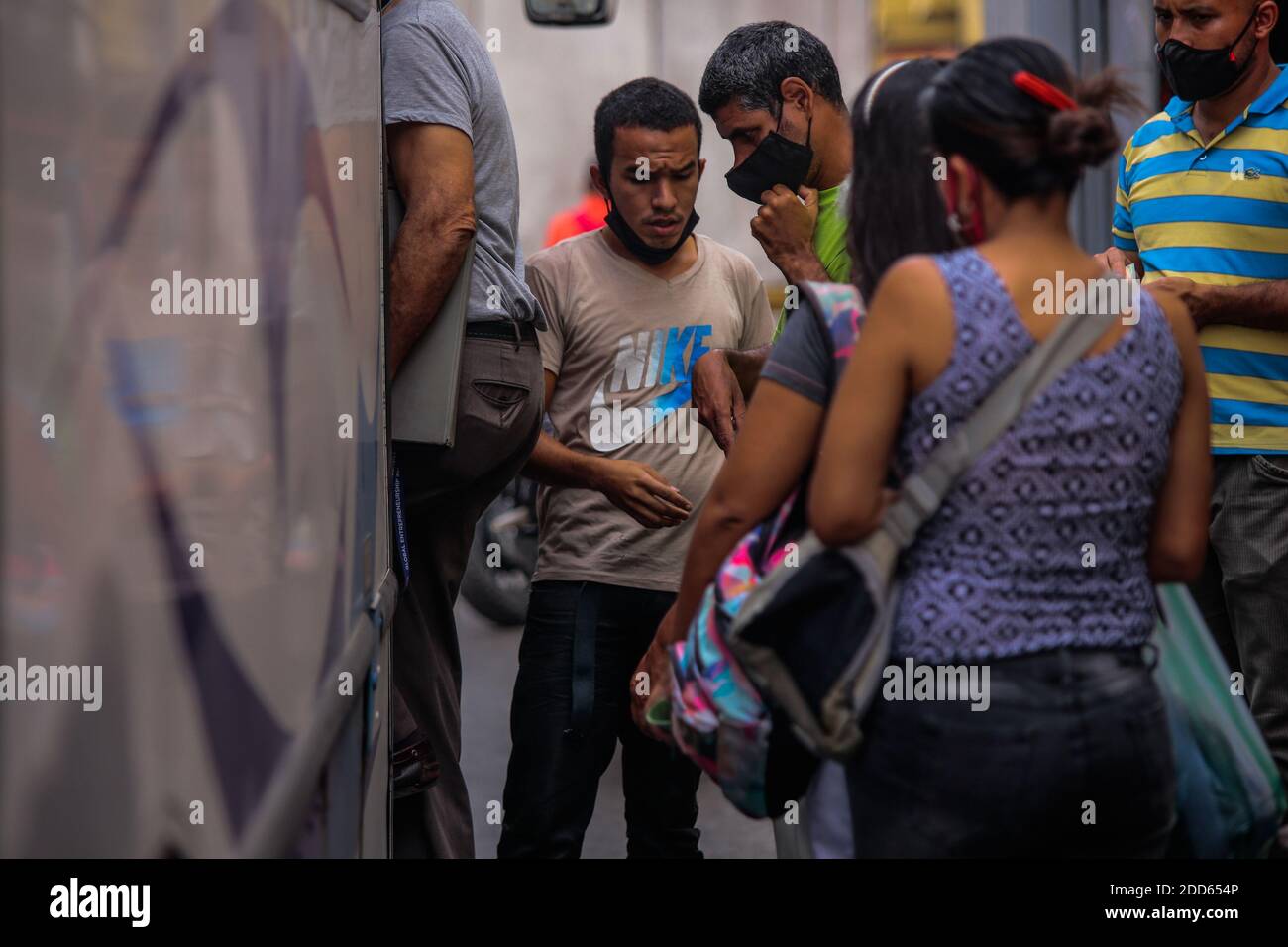 Caracas, Venezuela. November 2020. Ein Mann mit einer Maske auf überprüft Passagiere, bevor sie in einen Bus einsteigen. Viele Menschen auf der ganzen Welt tragen die obligatorischen Masken unter ihrer Nase oder sogar ihr Kinn mitten in der Corona-Pandemie. Nach Angaben des venezolanischen Gesundheitsministeriums sollen 100,143 Menschen im Land mit Covid-19 infiziert sein und die Sterblichkeitsrate beträgt 0.87 Prozent. Ende Oktober hatte Präsident Maduro behauptet, in Venezuela sei ein hochwirksames Mittel gegen das Corona-Virus entdeckt worden. Kredit: Rafael Hernandez/dpa/Alamy Live Nachrichten Stockfoto