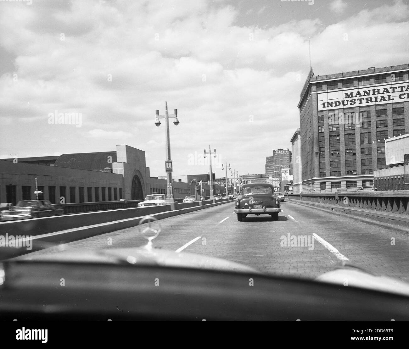 Historische Automobile aus den 1960er Jahren auf einer kopfsteingepflasterten Brücke, die das große Gebäude des Manhattan Industrial Center in der West 15th Street und 10th Avenue in New York, USA, verbindet. Das Gebiet des Industriezentrums war aufgrund seiner historischen Geschäftstätigkeit als Fleischpackungsviertel bekannt. Stockfoto