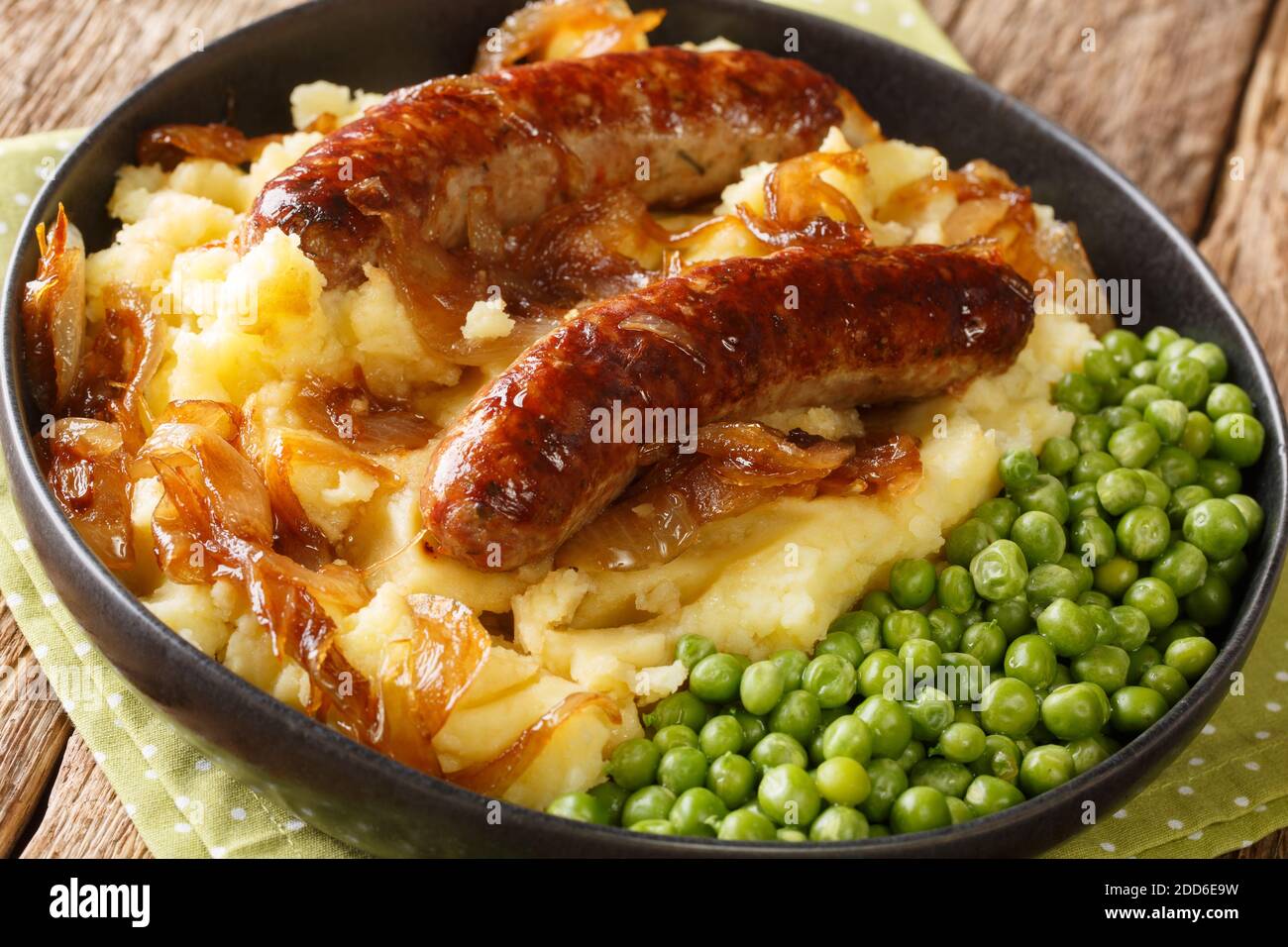 Irish Bangers and Mash ist ein Gericht, bestehend aus Würstchen mit Kartoffelpüree und Zwiebelsoße in der Nähe in der Platte auf dem Tisch serviert. Horizontal Stockfoto