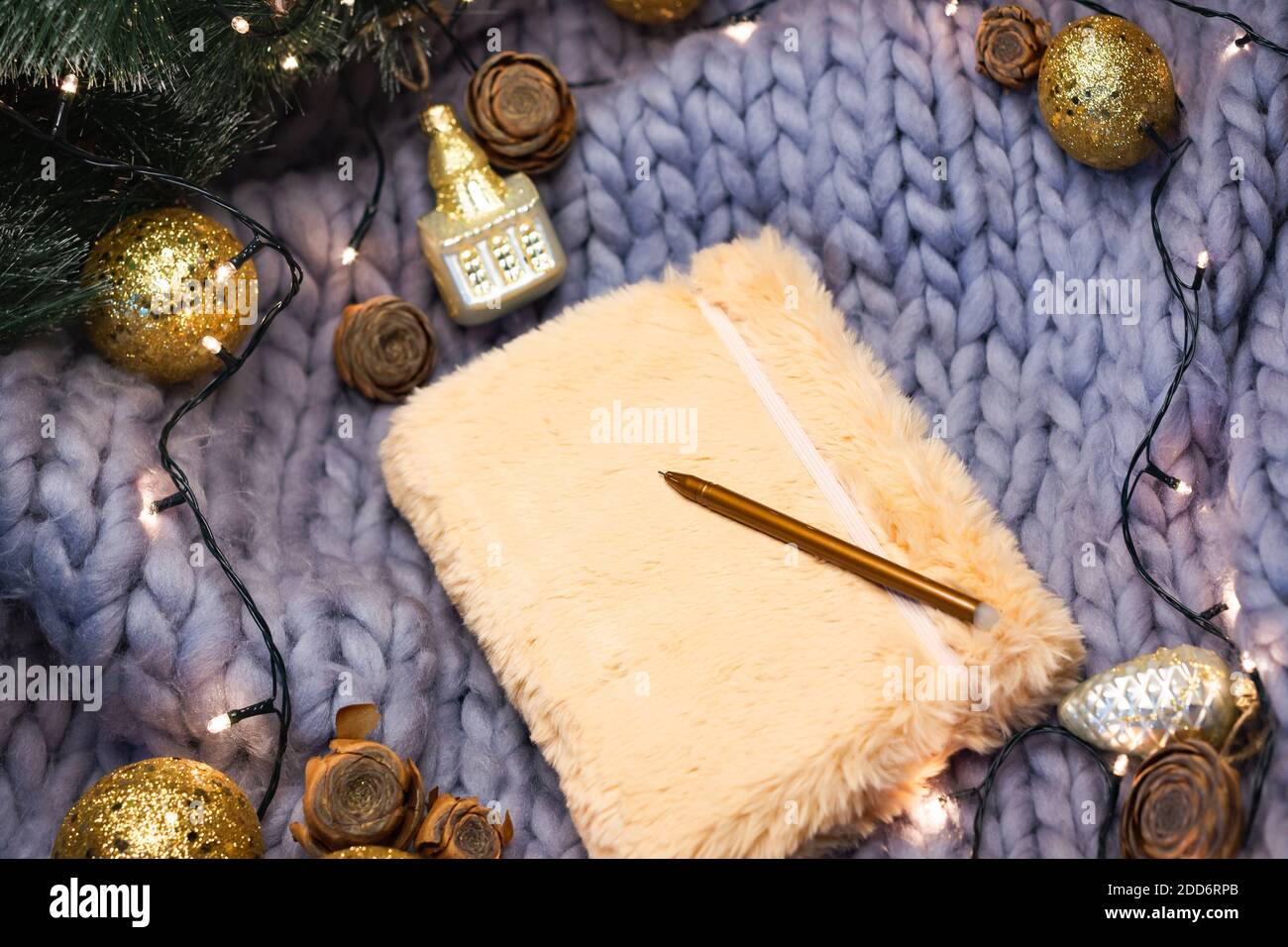Champagner-Notizbuch auf grauem Strickhintergrund mit weihnachtlichen Dekorationen, Flatlay Stockfoto