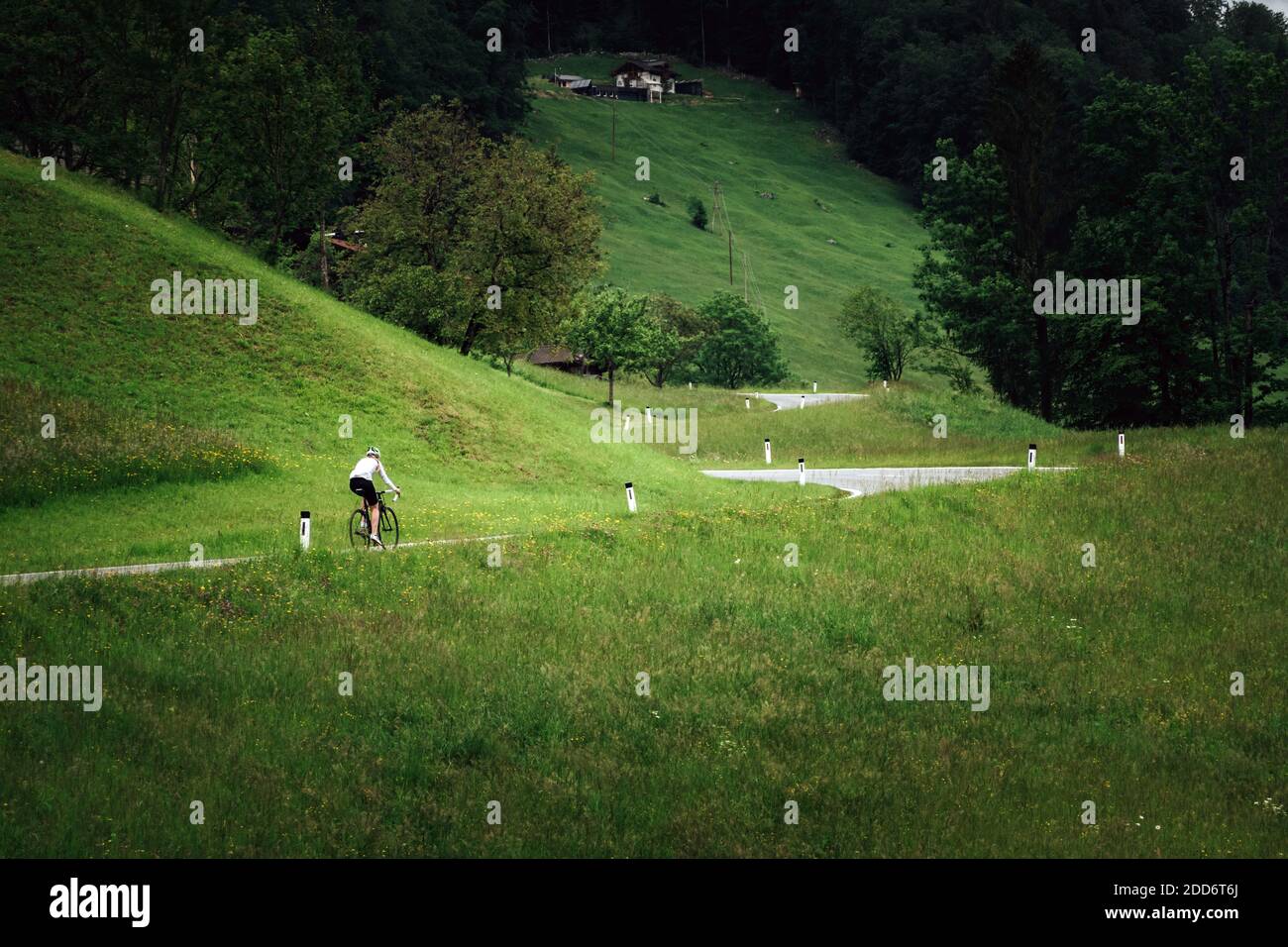 Eine Radfahrerin rast eine Straße in der Nähe von Krispl, Österreich. Stockfoto