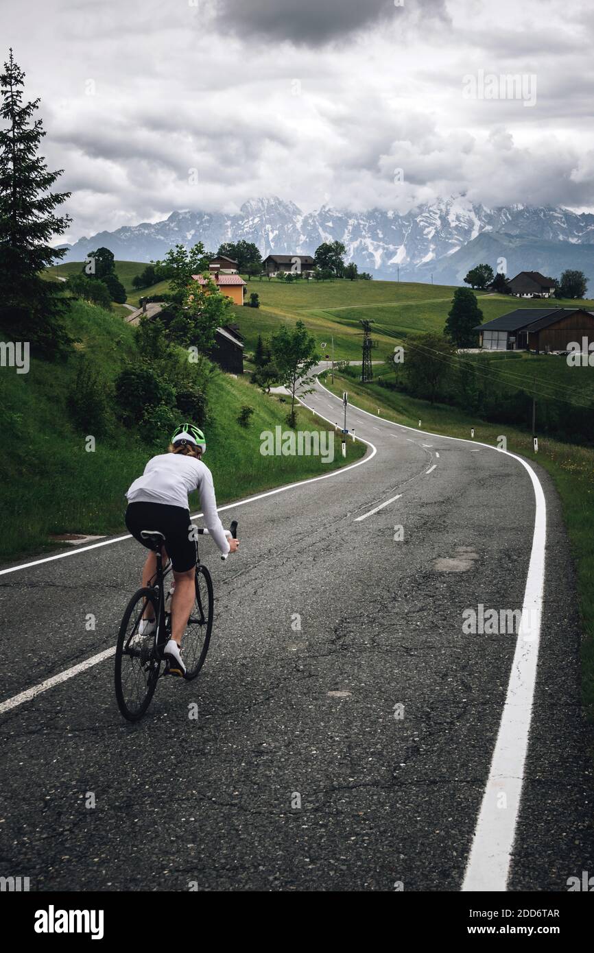 Eine Radfahrerin rast eine Straße in der Nähe von Krispl, Österreich. Stockfoto