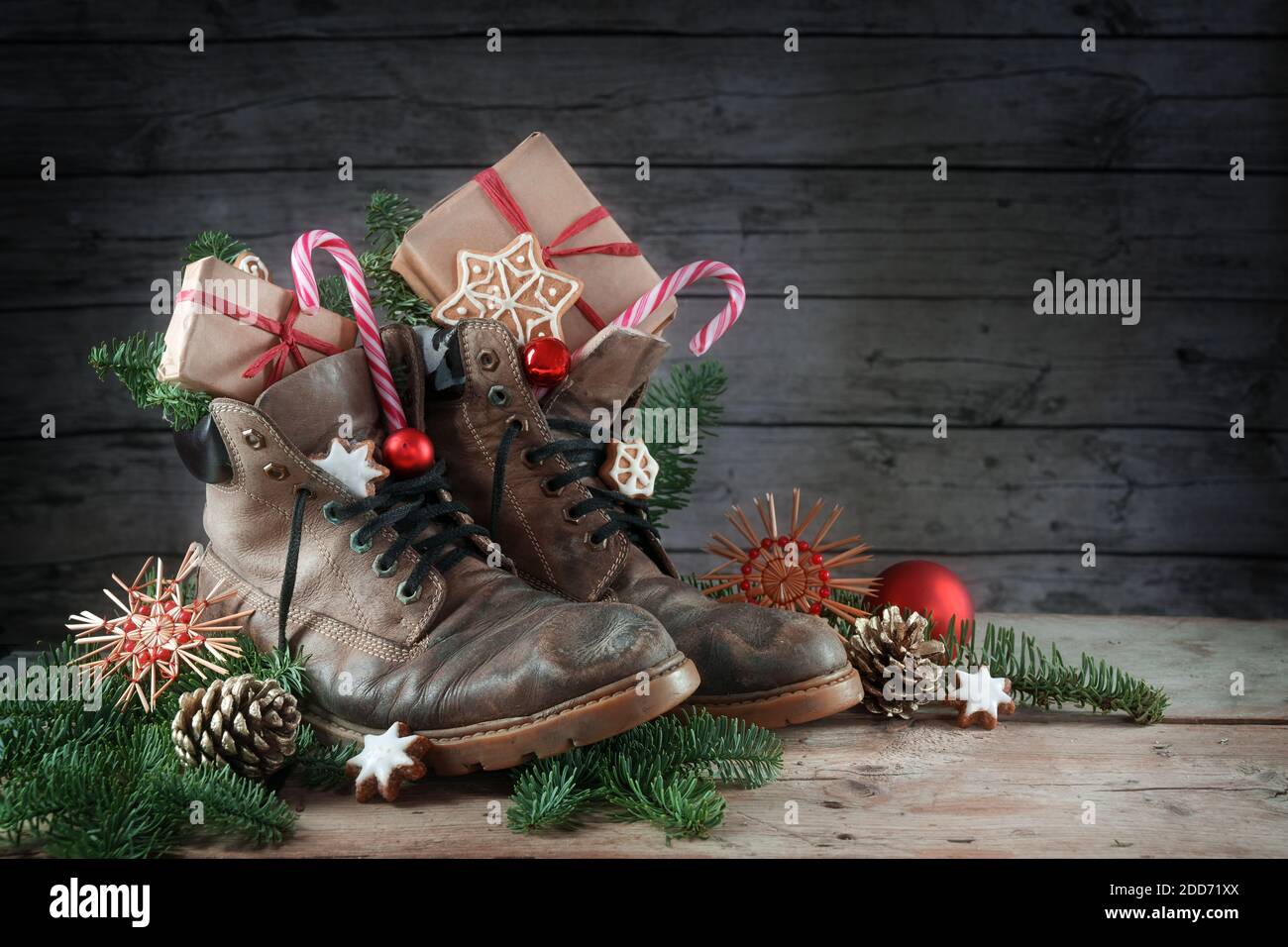 Alte Wanderschuhe gefüllt mit Süßigkeiten, Geschenken und Weihnachtsdekoration am Nikolaus-Tag, oder deutscher Nikolaus-Tag, am 6. Dezember ist es Tradition zu pu Stockfoto