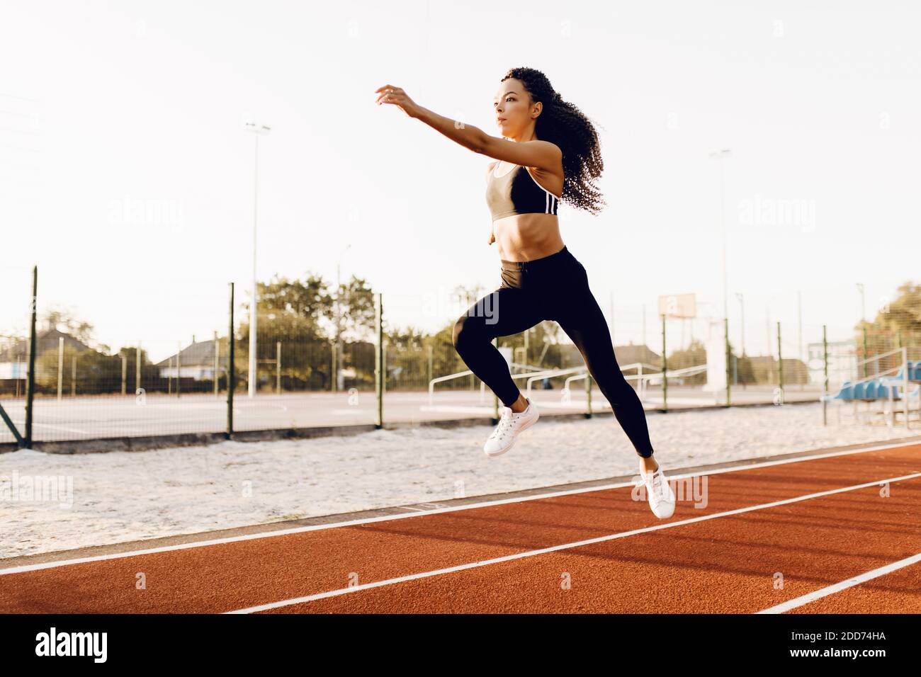 Athletische afroamerikanische Frau in der Sportkleidung Weitsprung am Stadion Im Freien Stockfoto