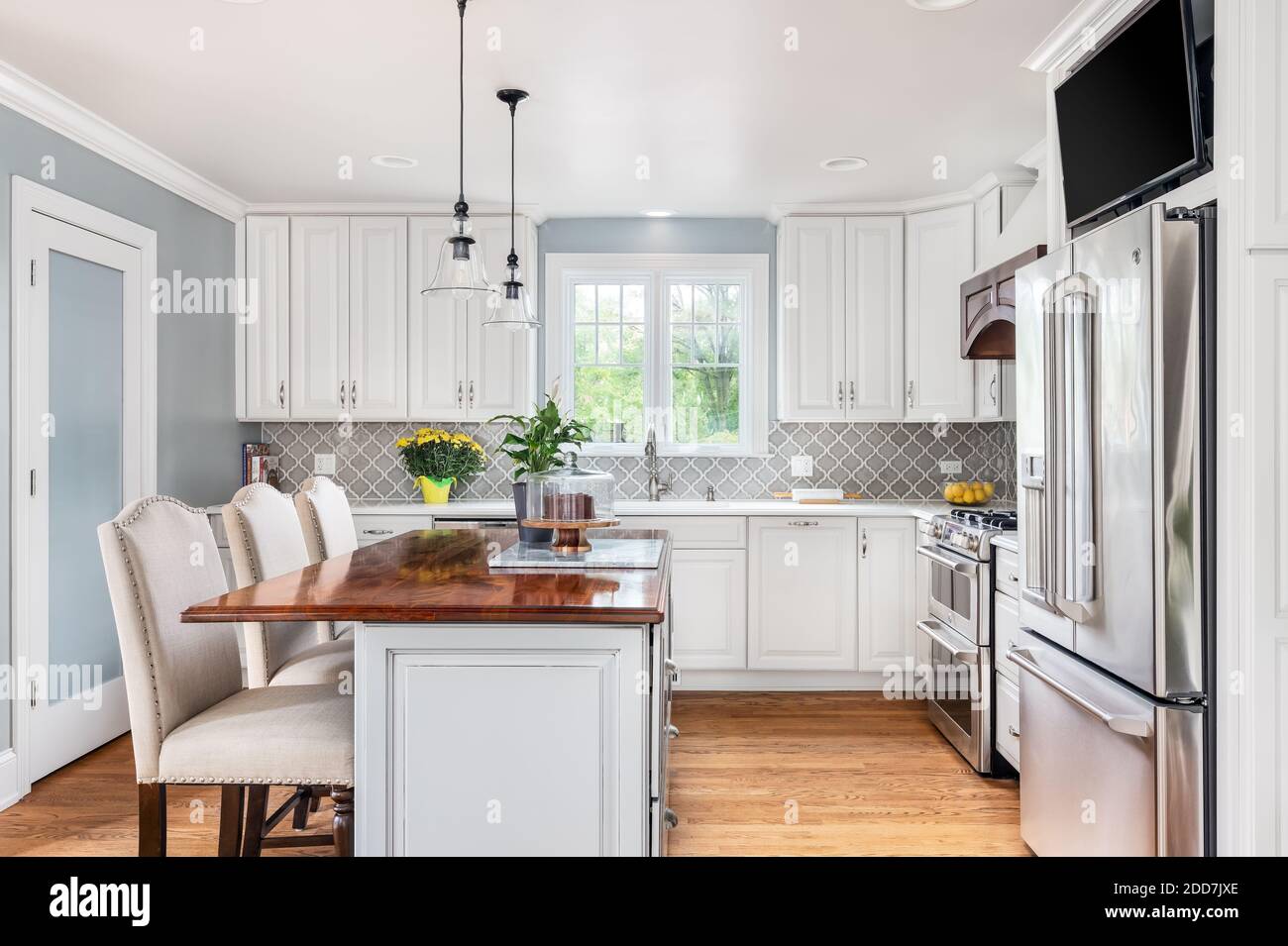 Eine neu renovierte Küche mit GE-Geräten aus Edelstahl, weißen und grauen Schränken und einem Fernseher über dem Kühlschrank. Stockfoto