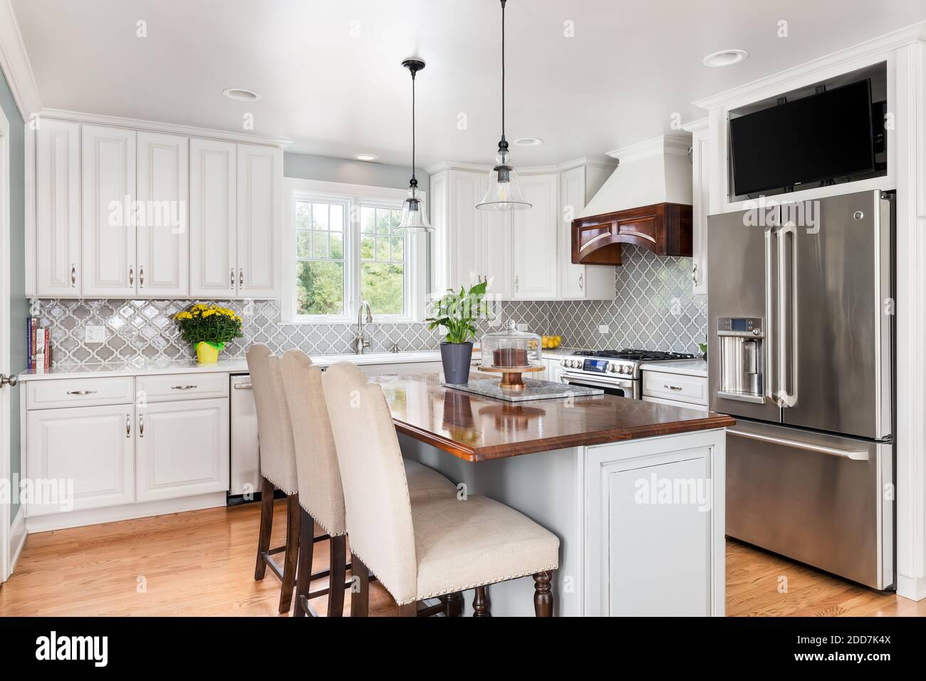 Eine neu renovierte Küche mit GE-Geräten aus Edelstahl, weißen und grauen Schränken und einem Fernseher über dem Kühlschrank. Stockfoto