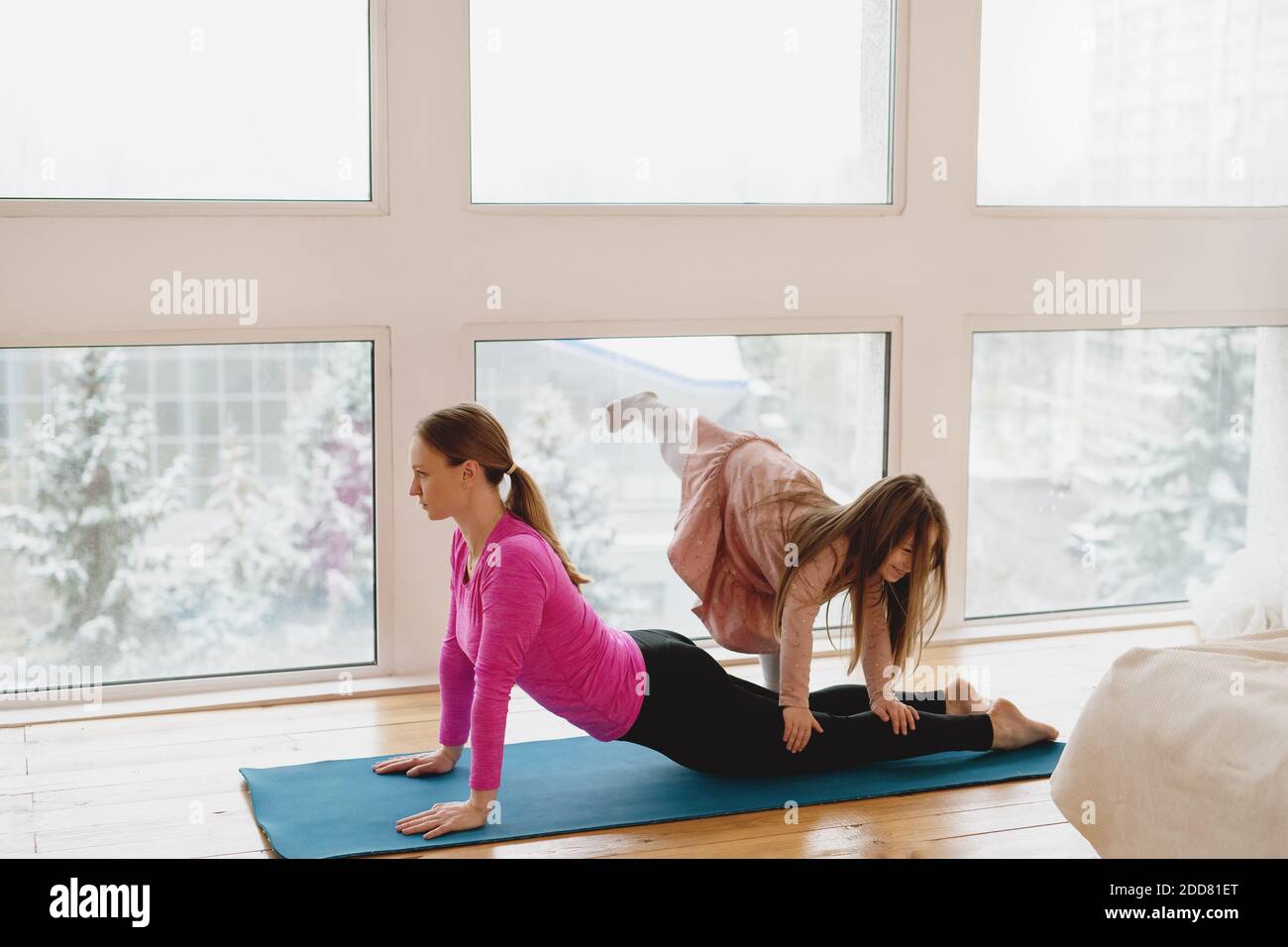 Mutter und ihre kleine Tochter machen zu Hause Yoga-Übungen. Home Workout-Konzept. Stockfoto