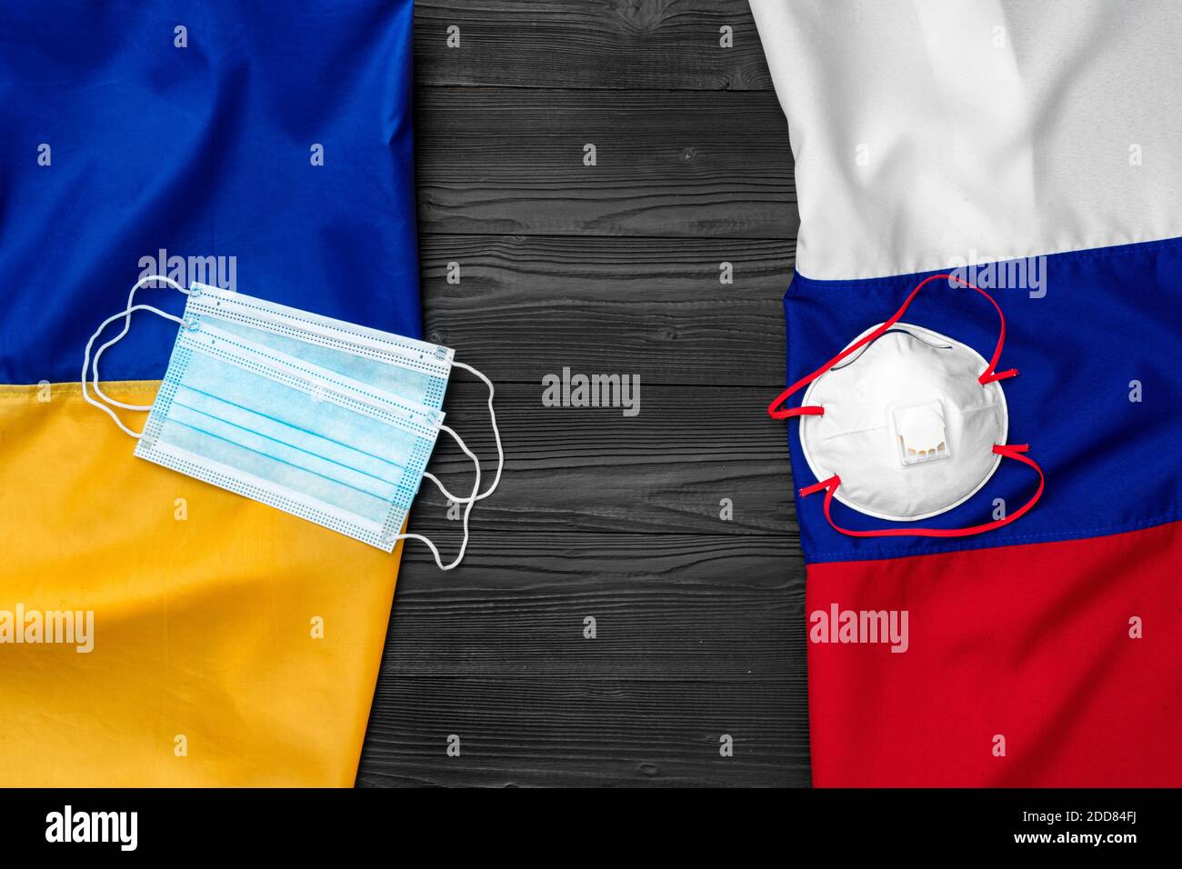 Flaggen von Russland und der Ukraine auf hölzernen Hintergrund mit medizinischen Masken Stockfoto