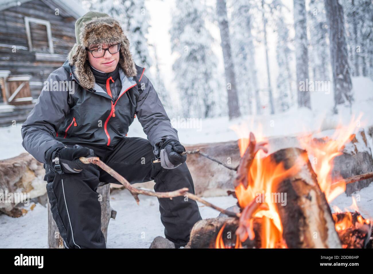 Person saß an einem Lagerfeuer und wärmte sich an einem eisigen kalten Wintertag am Polarkreis in Lappland, Finnland Stockfoto