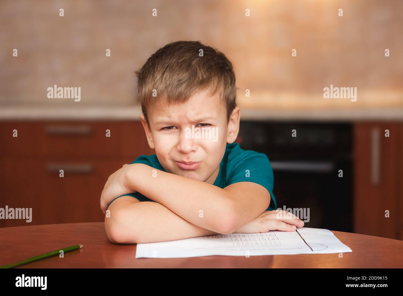 7 yeas alter Junge sitzt am Tisch in der Küche Und weinen, während Sie an harten Hausaufgaben arbeiten Stockfoto