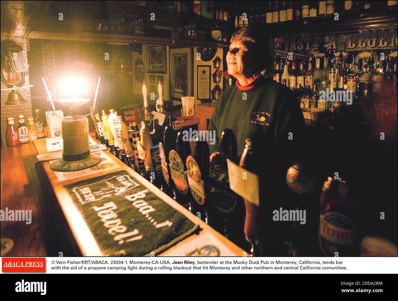 KEIN FILM, KEIN VIDEO, KEIN FERNSEHEN, KEIN DOKUMENTARFILM - © VERN FISHER/KRT/ABACA. 23034-1. Monterey-CA-USA. Jean Riley, Barkeeper im Mucky Duck Pub in Monterey, Kalifornien, neigt Bar mit Hilfe eines Propan Camping Licht während eines rollenden Blackout, die Monterey und anderen nördlichen und zentralen Kalifornien getroffen Stockfoto