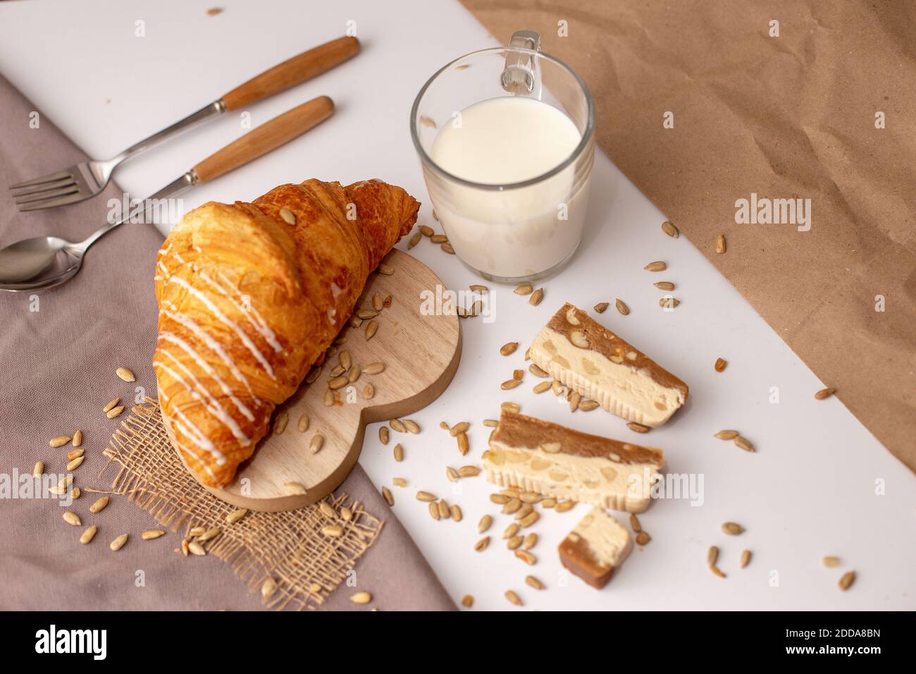 Großer Croissant, ein Glas Milch und Scheiben süßes Sorbet. Stockfoto