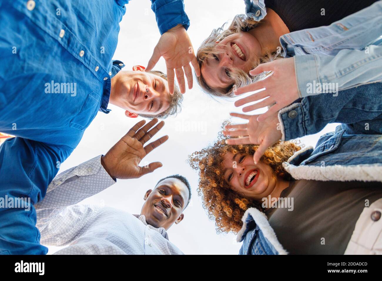 Lächelnde männliche und weibliche Freunde winken die Hände Stockfoto